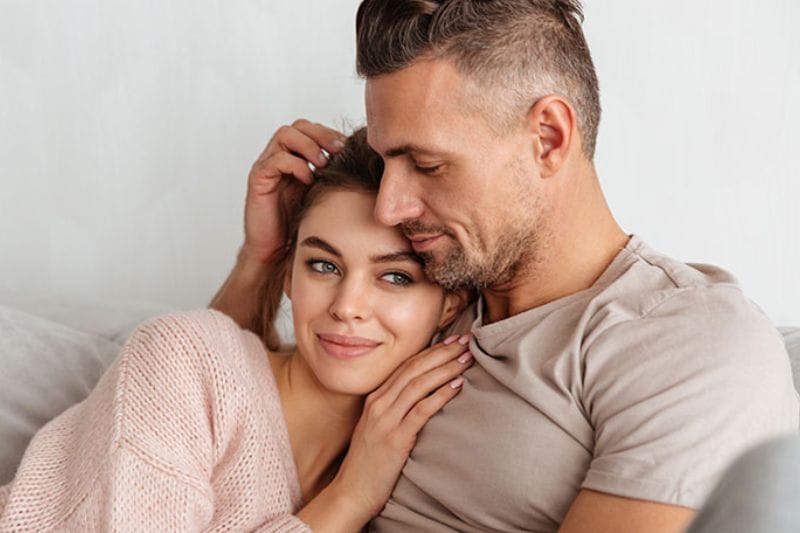 A relaxed couple sitting together on a living room couch, sharing a peaceful, quiet moment together at home